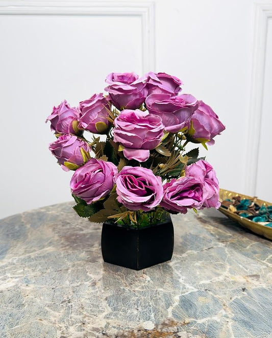 Bouquet of pink artificial roses in a black vase on a marble surface.