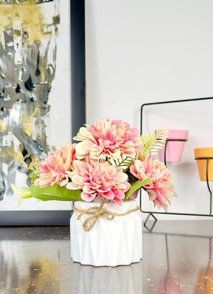 Decorative floral arrangement in a white vase on a table with abstract art in the background.