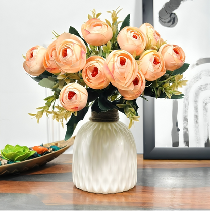 Bouquet of peach-colored flowers in a white vase on a wooden surface.