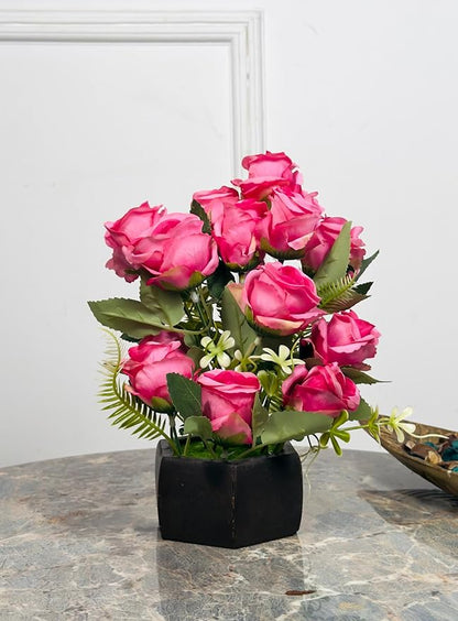 Bouquet of pink artificial roses in a black pot on a marble surface with a white wall background.