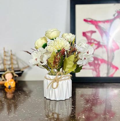 Small white vase with artificial flowers on a reflective surface