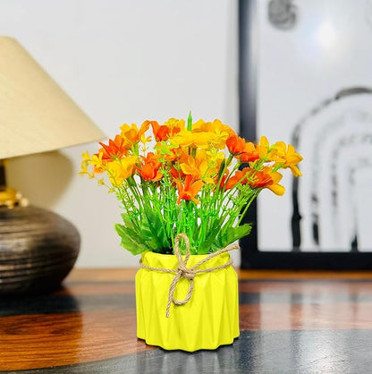 Yellow vase with orange and yellow flowers on a wooden surface