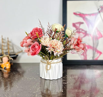 Small bouquet of flowers in a white vase on a reflective surface with a blurred background