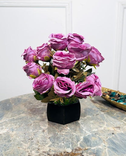 Bouquet of pink artificial roses in a black vase on a marble surface.