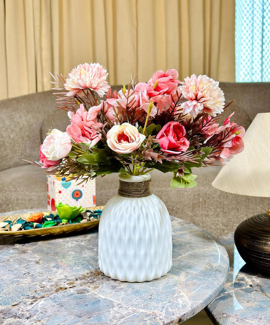 Dekorly Bouquet of pink flowers in a white vase on a marble table with a beige curtain in the background.