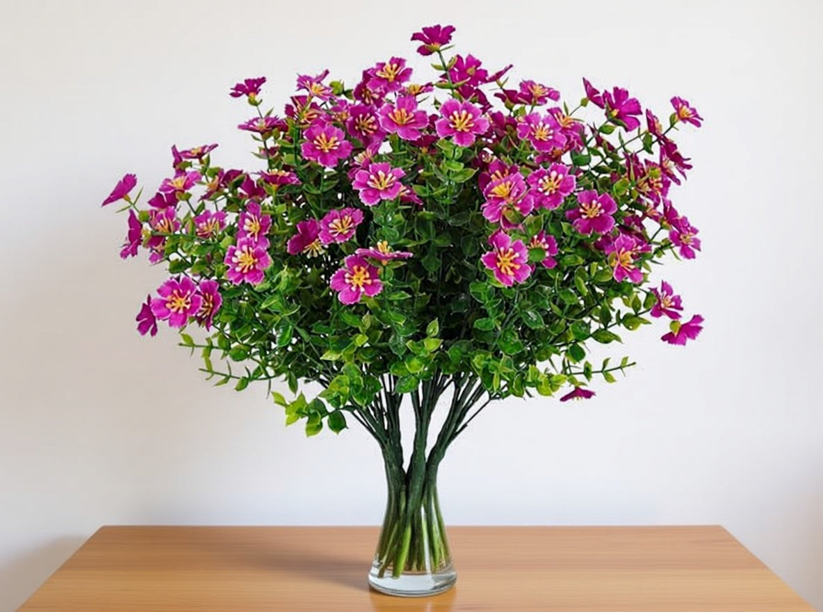 Bouquet of pink flowers in a clear vase on a wooden table with a white background