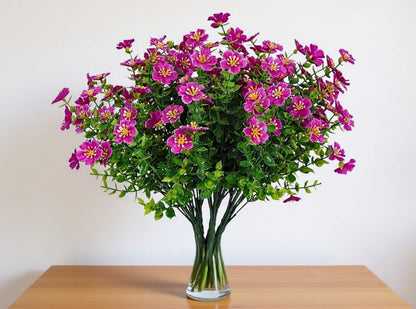 Bouquet of pink flowers in a clear vase on a wooden table with a white background