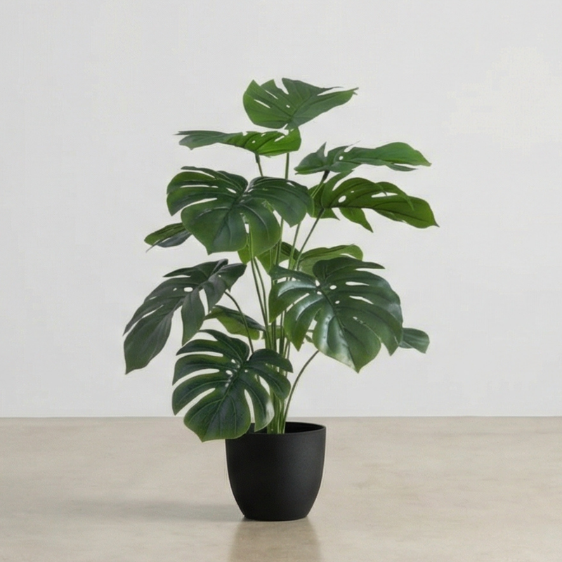 artificial monstera Potted plant with large green leaves on a light surface with a white background