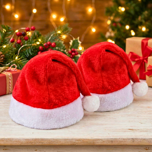 Red Santa hats on a wooden surface with Christmas decorations in the background.