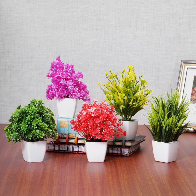 A set of artificial multicolored mini plants in pots, displayed on a table with a background of a wood texture.
